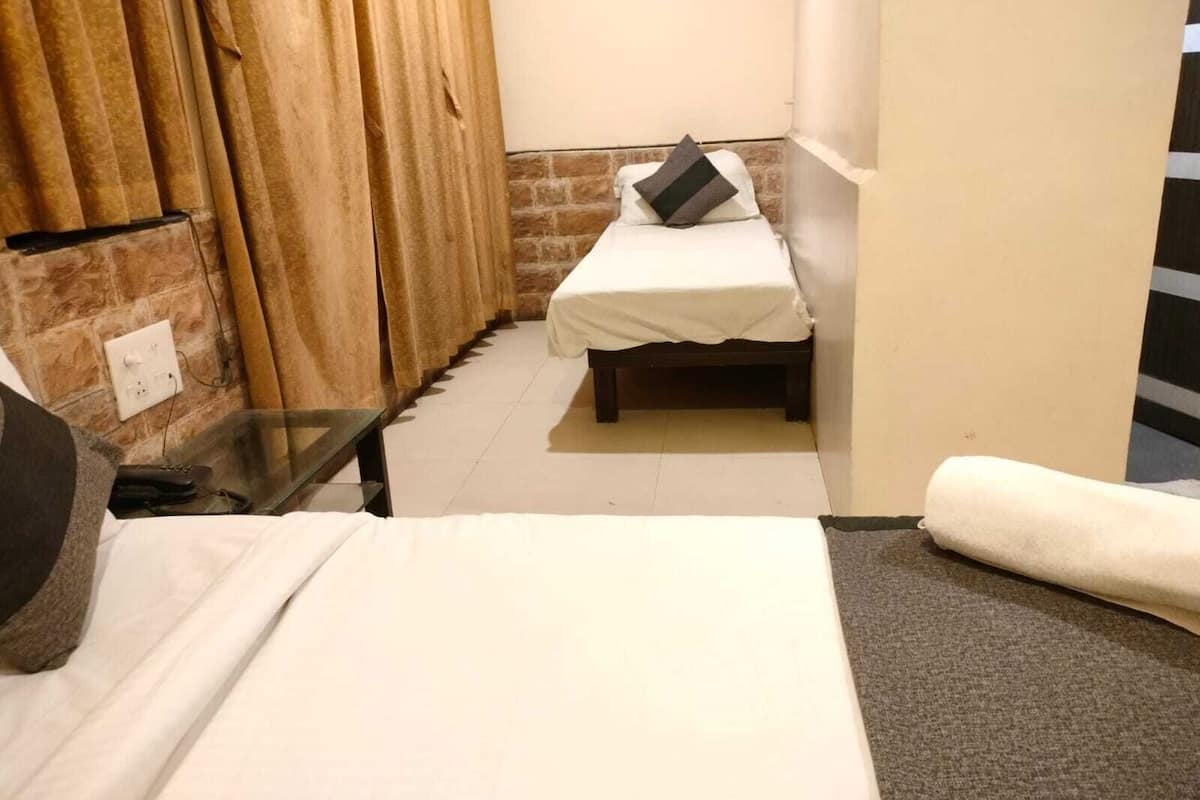 A small, narrow room with a bed, a table, and a curtain.