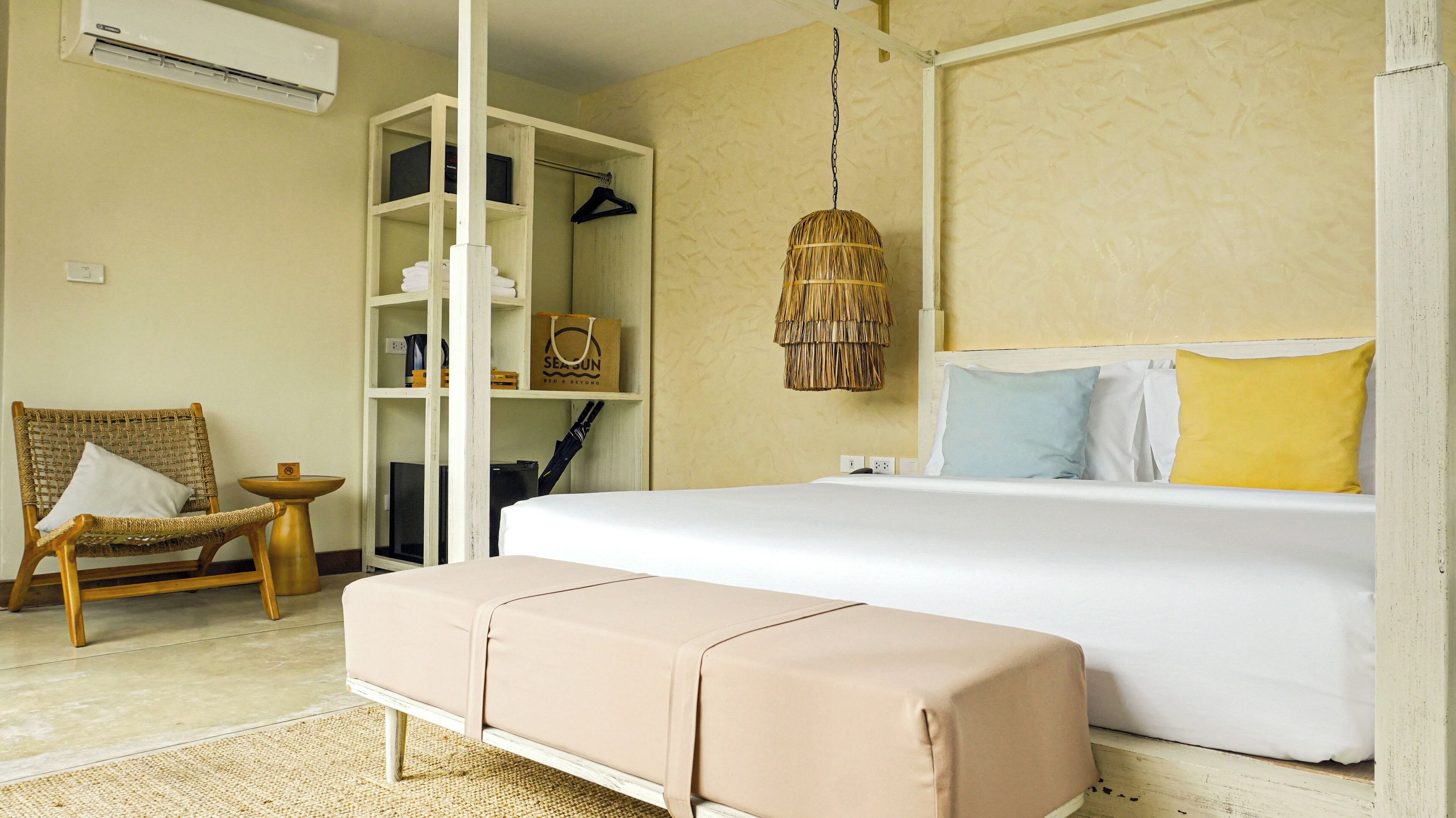 A bedroom with a bed, a chair, a wardrobe, and a hanging light fixture.