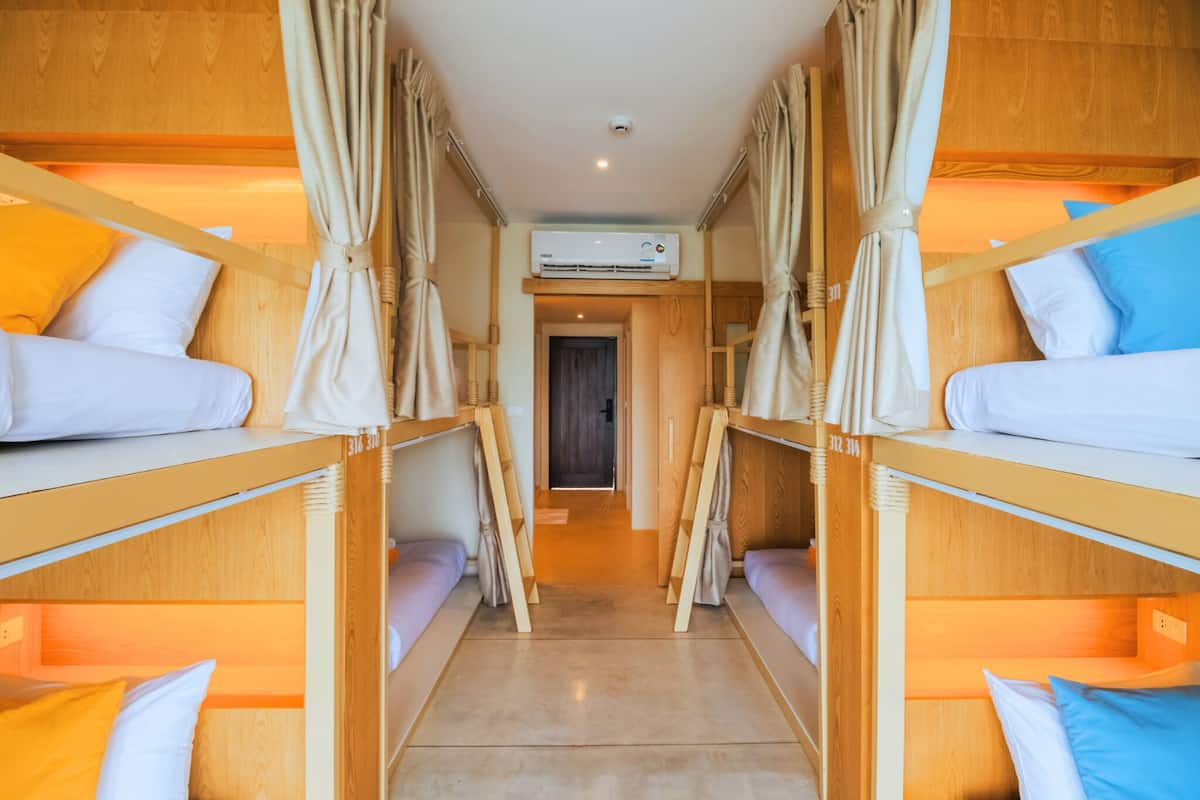 A room with bunk beds, an air conditioning unit, and curtains.