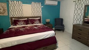 Une chambre à coucher comprenant un lit, un ventilateur de plafond, une chaise, une commode et un appareil de climatisation.