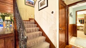 A staircase with a wooden handrail and carpeted steps leading to a room with a door.