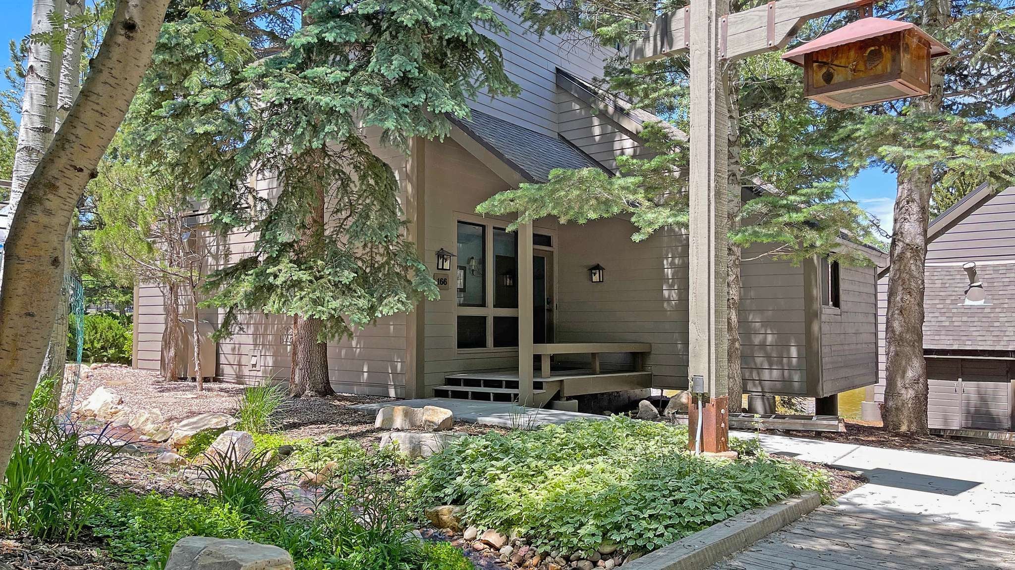 Une maison moderne dotée d’un porche abrité, d’un chemin en pierre et d’un jardin bien entretenu.