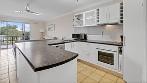 Una cocina moderna con armarios blancos, encimera de granito, horno empotrado y microondas.