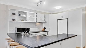 Una cocina moderna con una isla central, armarios blancos y un refrigerador de acero inoxidable.