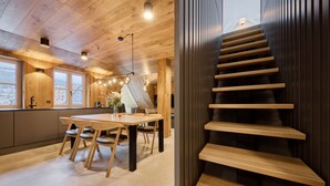 A modern kitchen with wooden cabinetry and a dining area with a wooden table and chairs. - Rooftop Vista Maisonette & Relaxing Bath by Interhome (Pec pod Snezkou)