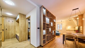 A modern interior with a wooden floor, a built-in bookshelf, a dining area with a table and chairs, and a ceiling light fixture. - Charming Mountain Oasis by Interhome (Pec pod Snezkou)