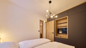 A bedroom with a bed, a wooden wardrobe, and a TV mounted on the wall. - Charming Mountain Oasis by Interhome (Pec pod Snezkou)