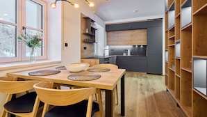 A modern kitchen with dark cabinets, a wooden dining table, and a chandelier. - Charming Mountain Oasis by Interhome (Pec pod Snezkou)