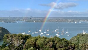 Eine Küstenansicht mit Booten, einem Regenbogen und einer hügeligen Landschaft.