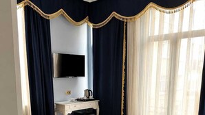 Hotellihuone, jossa on kaksi sänkyä, työpöytä, jossa on televisio, puhelin ja kahvinkeitin.