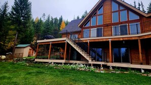 A two-story log cabin with a balcony and a covered deck area. - Ponderosa Glen @ Ashley Lake (Kila)