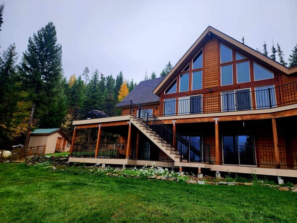 A two-story log cabin with a balcony and a covered deck area. - Ponderosa Glen @ Ashley Lake (Kila)