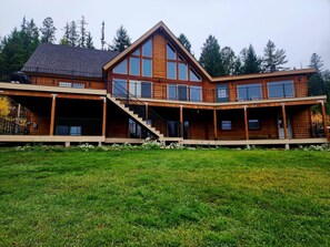 A two-story wooden house with a large front porch, a garage, and a staircase leading to the upper level. - Ponderosa Glen @ Ashley Lake (Kila)