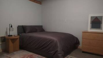 Une chambre à coucher avec un lit, une commode, une table de chevet et un tapis.