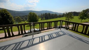 Ein Balkon mit Blick auf eine grüne Landschaft und ferne Hügel.