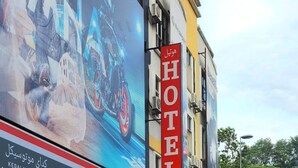 A hotel with a prominent red sign, a large advertisement for a motorcycle, and a visible storefront for a motorcycle dealership.