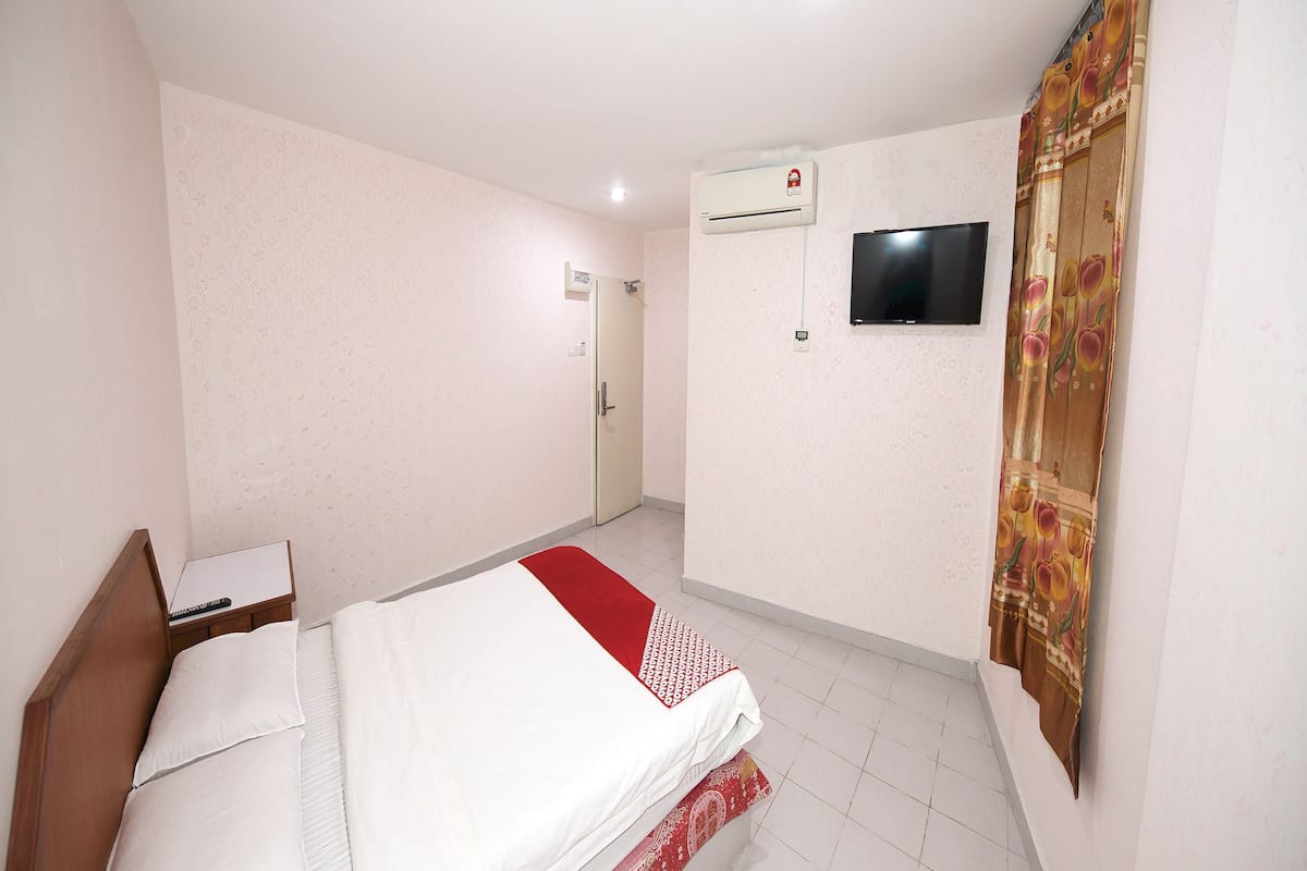 Ein Hotelzimmer mit einem Bett, einem Fernseher, einer Klimaanlage und einer Tür.