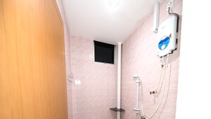A small bathroom with pink tiles, a toilet, a sink, and a shower unit.