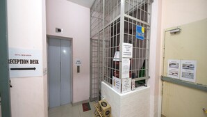 A reception desk, a window with a metal grid, and a door with a sign.