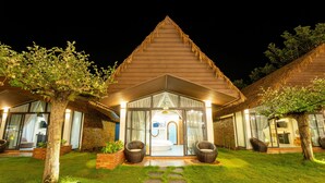 A two-story house with a thatched roof, a glass entrance, and a well-maintained lawn. - Apple House & Coffee (Ho Chi Minh City)