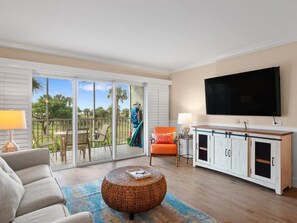 A living room with a sofa, a round coffee table, a TV, and a cabinet. - Superb Beachfront Residence on Captiva (Captiva)