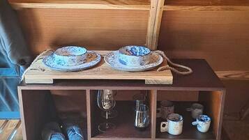 A wooden cabinet with a shelf containing folded towels, a glass, and a decorative item.
