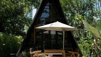 A triangular building with a pool in front, surrounded by greenery.