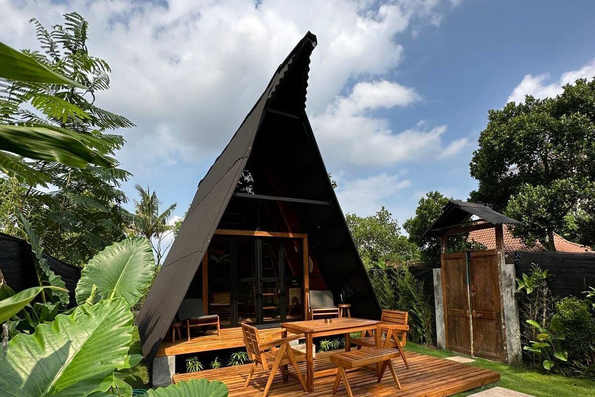 A modern, triangular-shaped building with a wooden deck and outdoor seating area.
