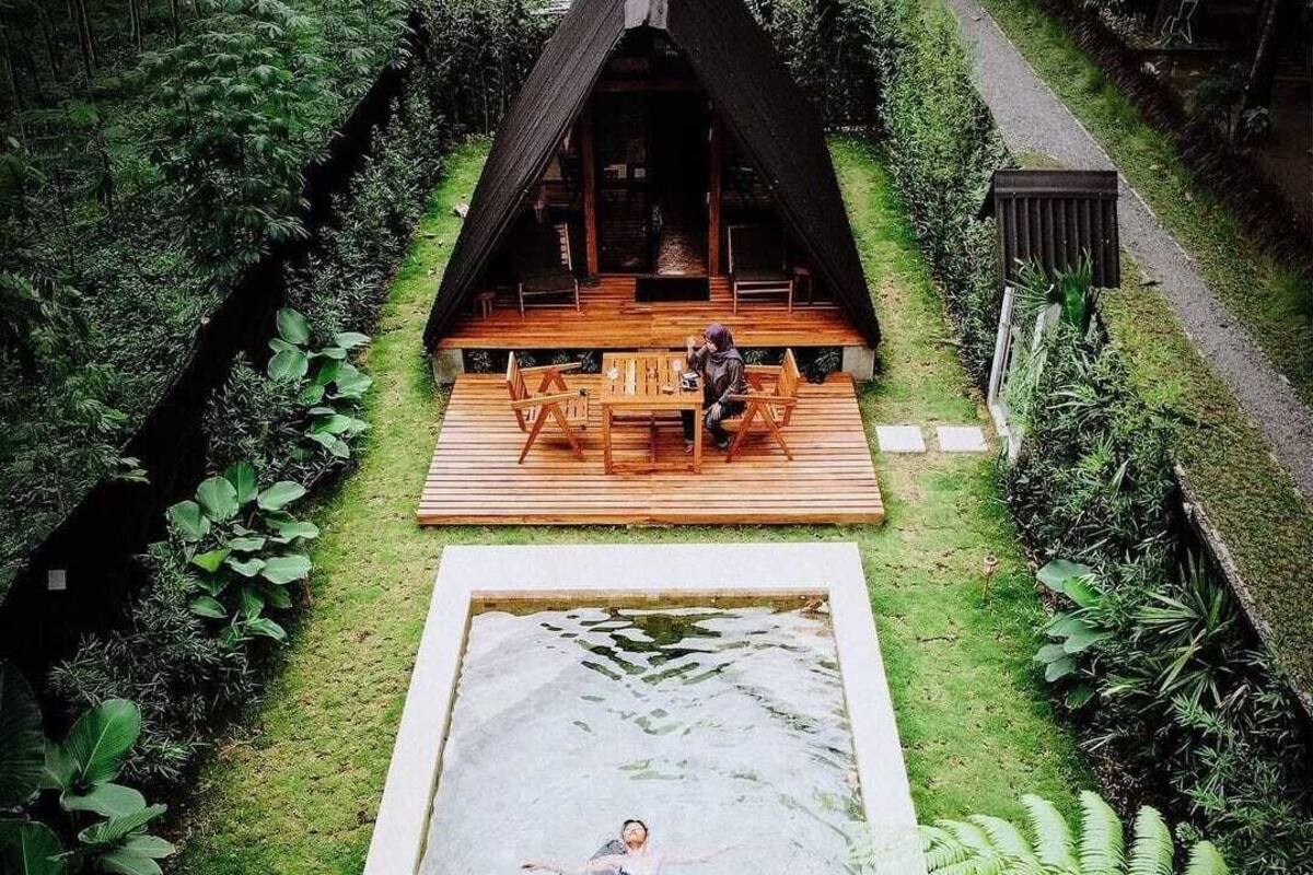 A wooden deck with a table and chairs, a small pool, and lush greenery surrounding the area.