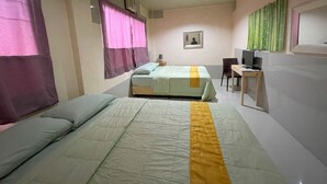 A bedroom with two beds, a desk, a chair, a television, and a window with curtains. - BnT Inn Cebu powered by Cocotel (Lapu-Lapu)