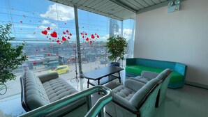 A modern interior with a glass wall, a green sofa, and a table. - BnT Inn Cebu powered by Cocotel (Lapu-Lapu)