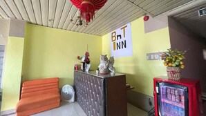 A hotel reception area with a red lantern, a reception desk, a fan, a vending machine, and a sign that reads "BnT INN". - BnT Inn Cebu powered by Cocotel (Lapu-Lapu)