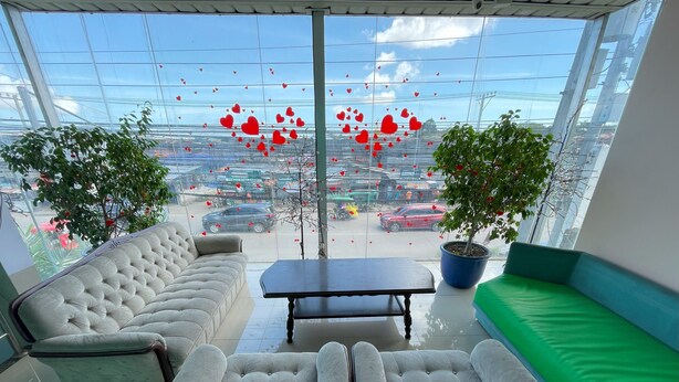 A modern living room with a sofa, armchairs, and a coffee table, featuring large windows with a city view. - BnT Inn Cebu powered by Cocotel (Lapu-Lapu)