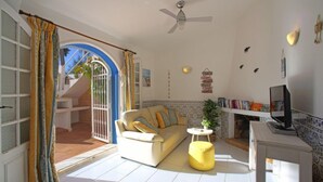 A living room with a sofa, a television, and a ceiling fan.