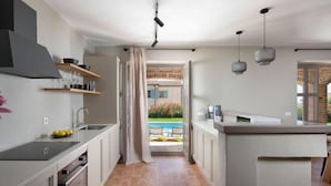 A modern kitchen with a central island, a dining area with outdoor seating, and a view of a garden. - Vacation home Seseli by Interhome (Poreč/Sv. Lovreč)