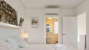 A hotel room with a bed, a wall-mounted air conditioner, a painting, and a potted plant. - Residencial Koma by Interhome (Torrevieja)