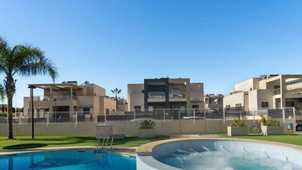 A swimming pool with a hot tub, surrounded by modern buildings and a palm tree. - Residencial Koma by Interhome (Torrevieja)