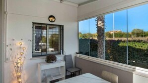A modern room with a large window, a small desk, a chair, and a table. - Residencial Koma by Interhome (Torrevieja)