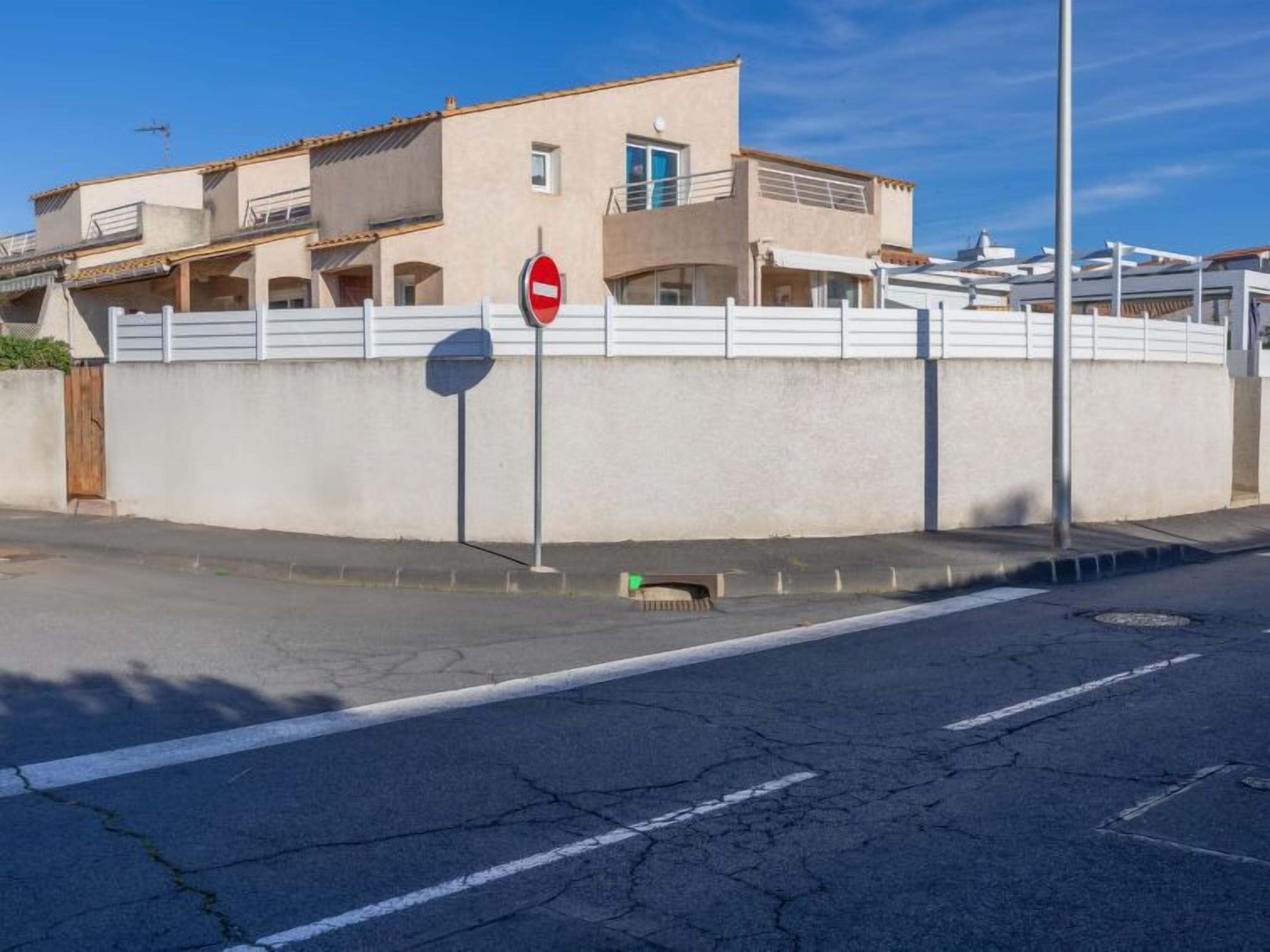 A residential building with a beige facade, a gated entrance, and a no-entry sign.