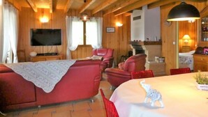 A cozy wooden cabin interior with a red sofa, a television, and a fireplace. - Le Chêne Vert by Interhome (Loupiac)