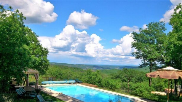 A swimming pool with lounge chairs and umbrellas, surrounded by lush greenery and trees. - Le Chêne Vert by Interhome (Loupiac)