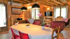 A cozy dining area with a wooden ceiling, a round table, red chairs, and pendant lighting. - Le Chêne Vert by Interhome (Loupiac)