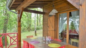 A wooden deck with a table and red chairs, surrounded by a wooden fence and trees. - Le Chêne Vert by Interhome (Loupiac)
