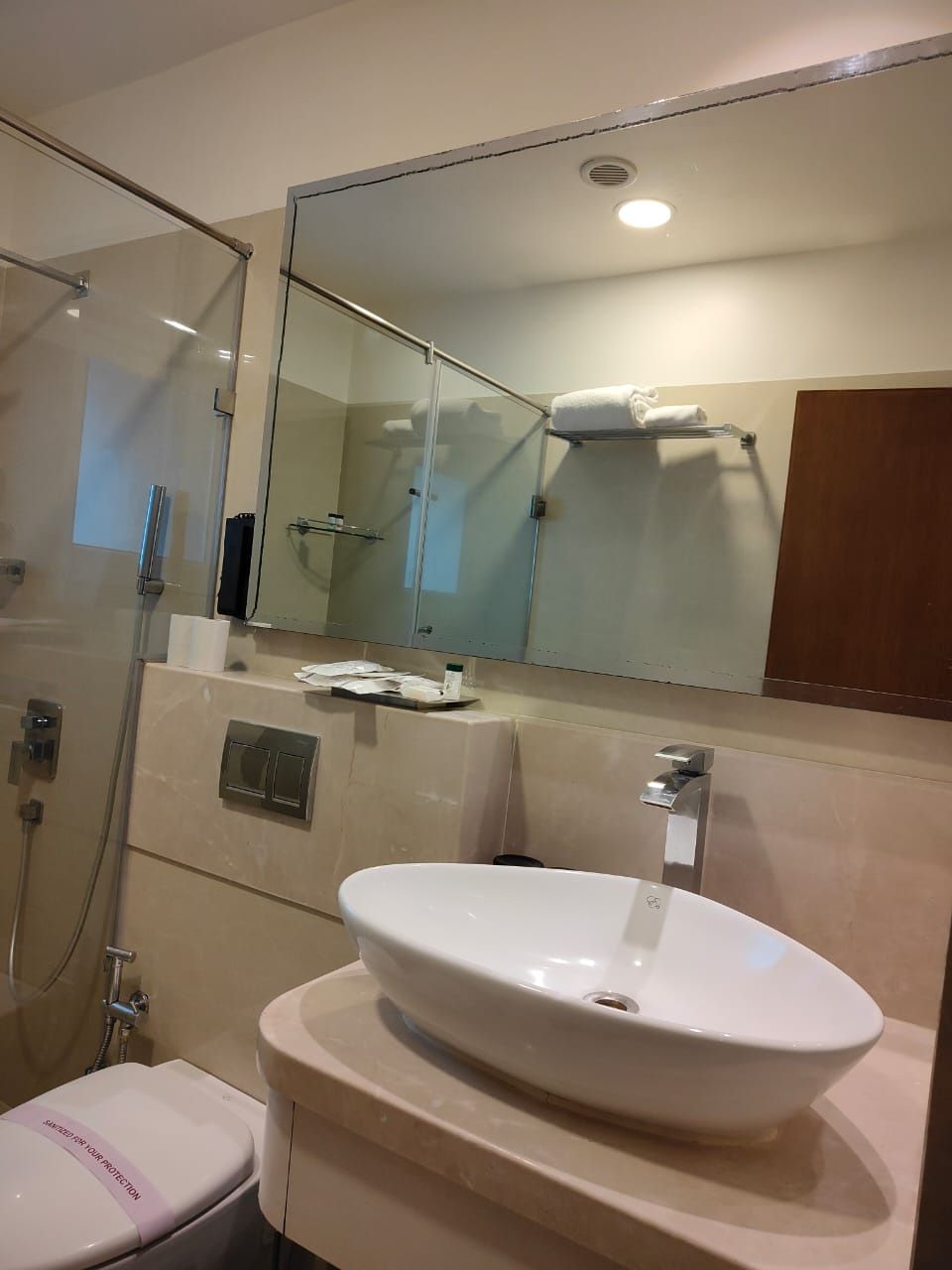 A bathroom with a glass shower enclosure, a white sink, and a mirror above the sink.