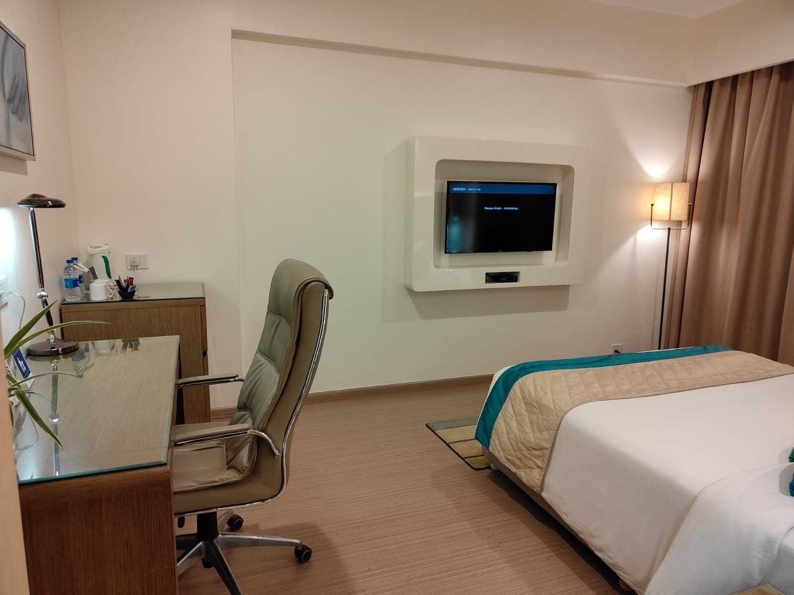 Une chambre d’hôtel équipée d’un lit, d’un bureau, d’une chaise, d’une télévision et d’une lampe.