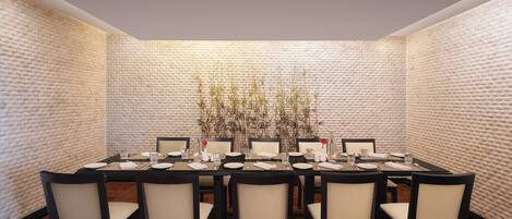 A dining room with a brick wall, a long table set for eight, and chairs.