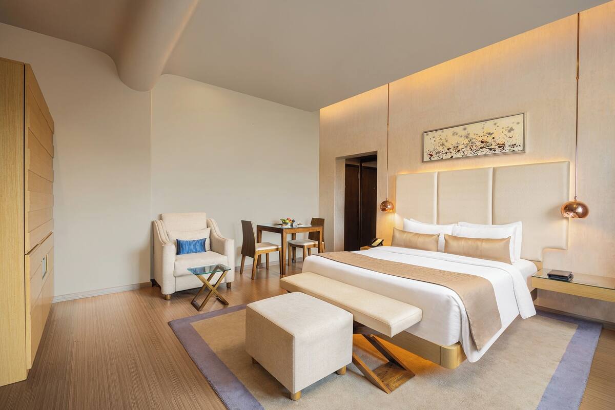 Ein modernes Hotelzimmer mit einem großen Bett, einer Sitzecke mit Tisch und Stühlen, einem Sofa und einem Holzschrank.
