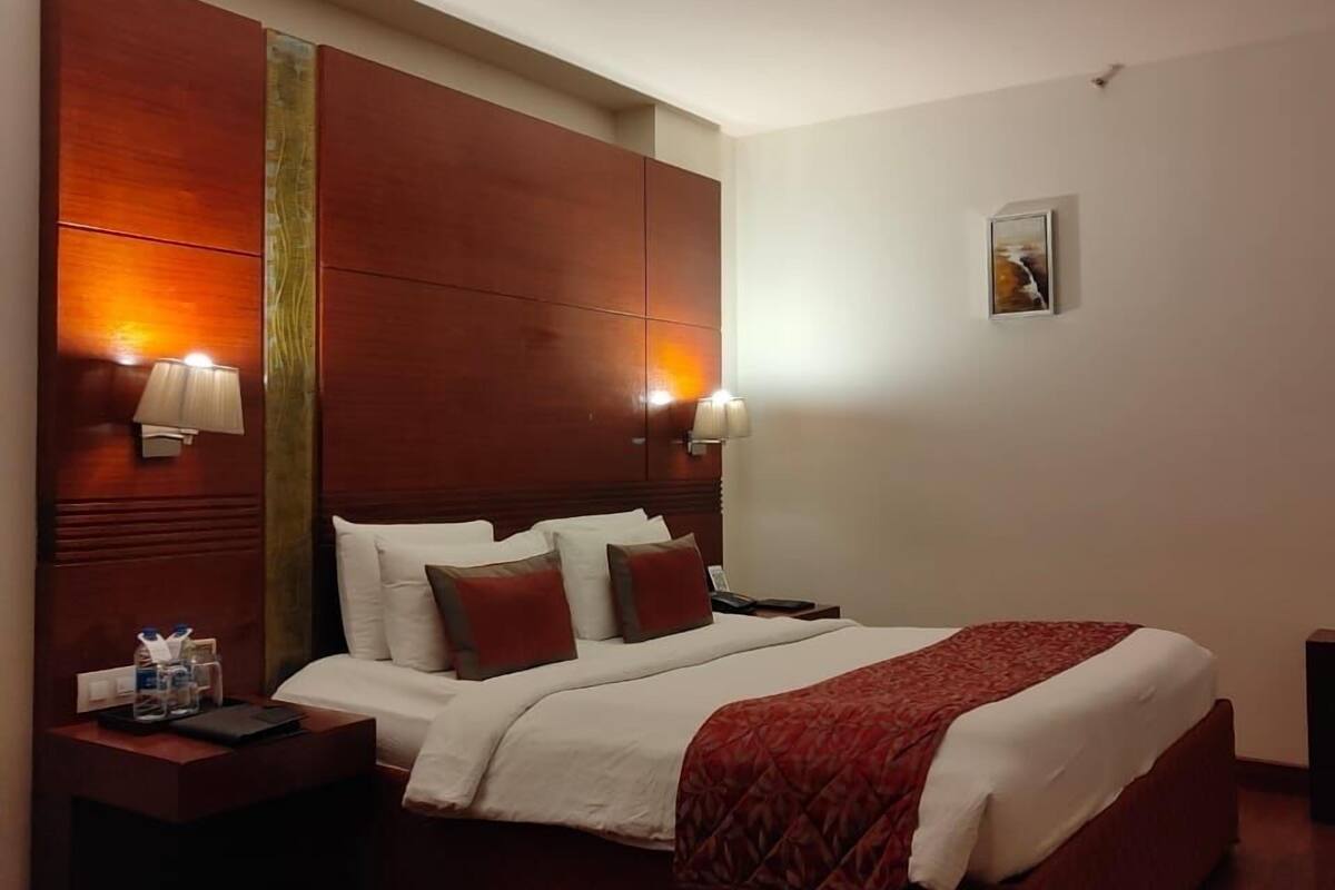 Ein Hotelzimmer mit einem großen Bett, einem hölzernen Kopfteil, zwei Nachttischlampen, einem Nachttisch und einem kleinen Tisch mit einer Lampe.