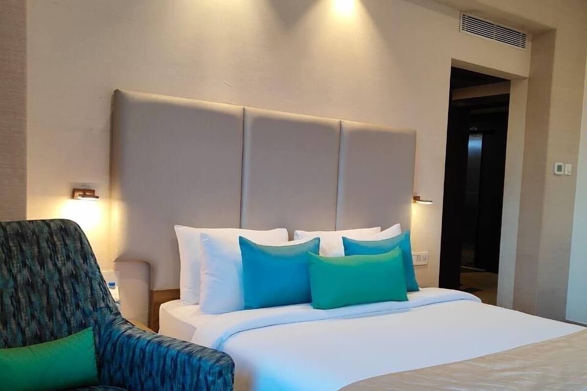 Ein Hotelzimmer mit Bett, Sessel und kleinem Tisch.