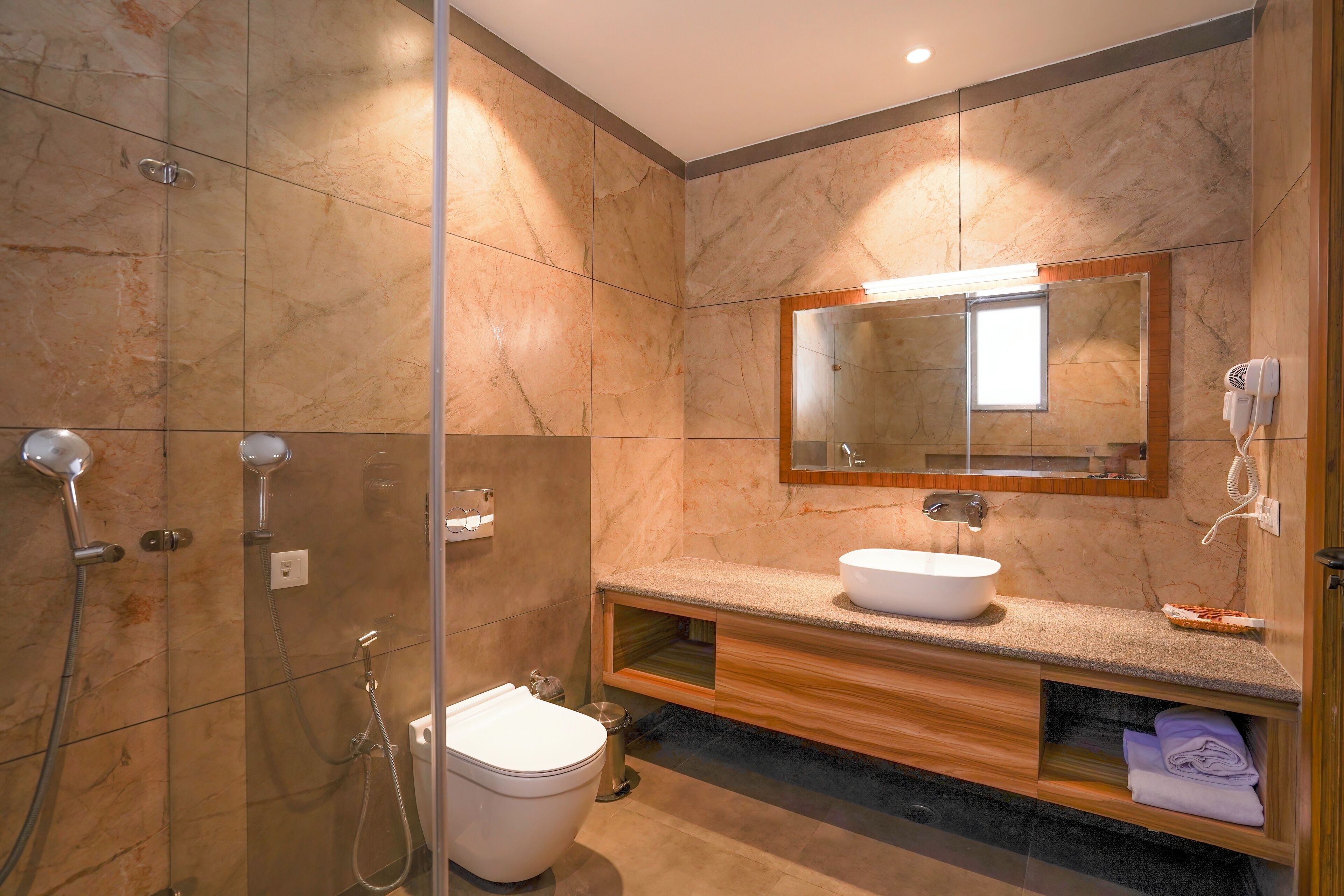 A modern bathroom with a glass-enclosed shower, a white sink, and a wooden vanity.